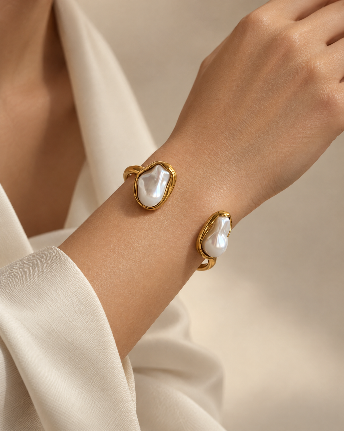 Close-up editorial jewelry photograph of a bracelet on a wrist. The arm is softly bent with a natural, elegant pose. Neutral beige or soft ivory background. Warm diffused studio lighting with subtle shadows to sculpt the wrist and enhance the bracelet’s reflective surfaces. Premium fashion campaign style, cinematic softness, shallow depth of field, polished skin texture, sophisticated and modern aesthetic. @Isla Pearl Bracelet